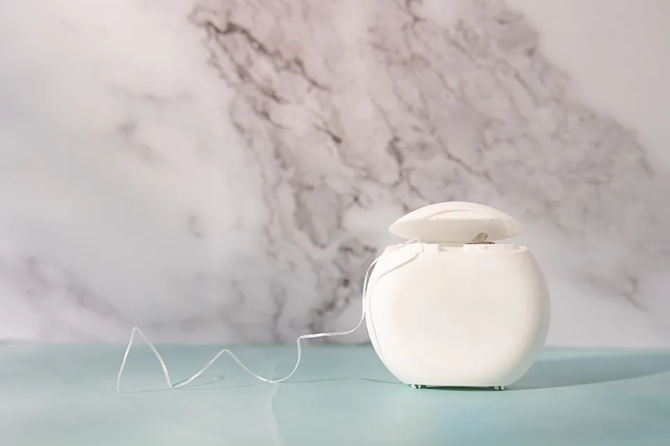 A container of floss on a marble shelf