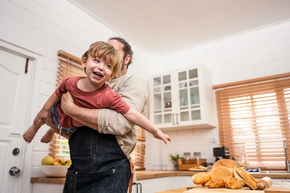 A parent and a young child laughing together at home