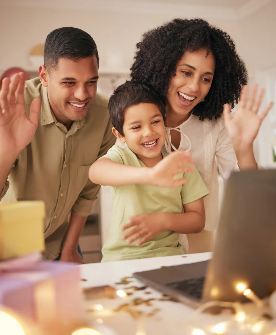 A family waving at a laptop on a video call
