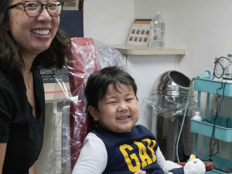 Dr. Nguyen beside a smiling child in a treatment room